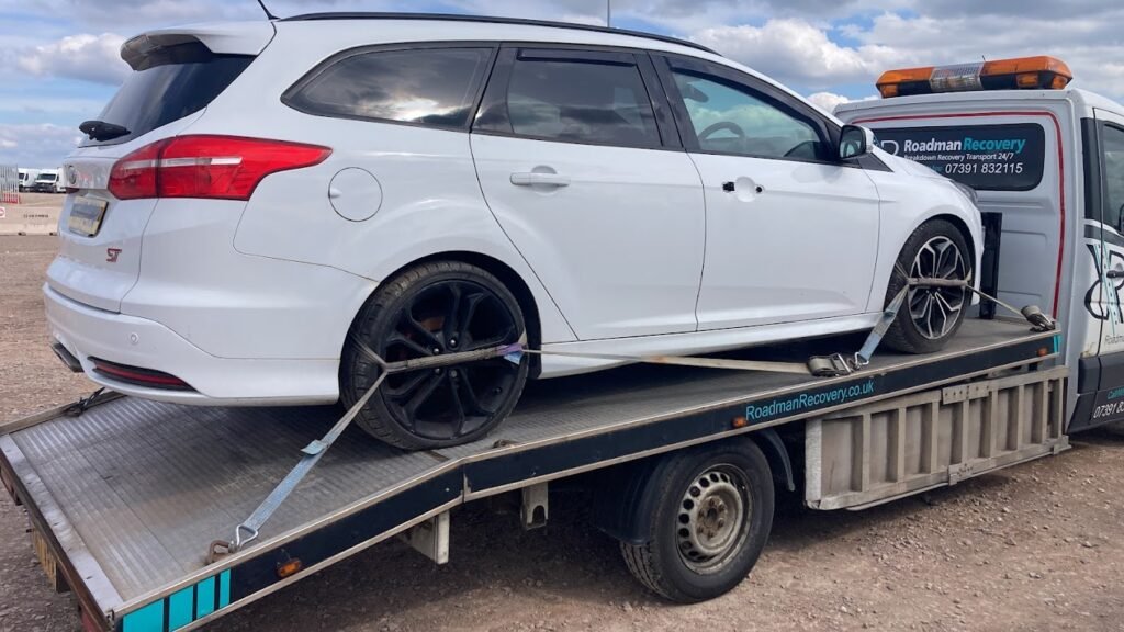 White car on a flatbed recovery truck operated by Roadman Recovery in Bradford. Roadman Recovery provides 24/7 vehicle recovery and towing services. Keywords: vehicle recovery Bradford, car towing service Bradford, emergency roadside assistance Bradford.